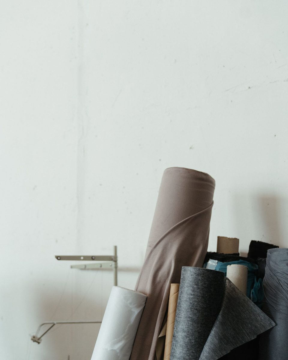 Rolls of cloth leaning against a white wall in a workshop